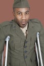 Portrait of an African American US military officer with crutches over brown background