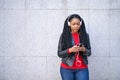 Portrait of a smiling African-American woman with a cell phone is chatting or listening to music on the streets of the city. The Royalty Free Stock Photo