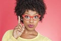 Portrait of an African American woman in retro glasses pointing upward over colored background