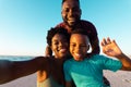 Portrait of african american woman taking selfie with happy husband and son at beach against sky Royalty Free Stock Photo