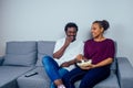 Portrait of african american young couple sitting sofa watching a movie and eating pop corn on living room Royalty Free Stock Photo