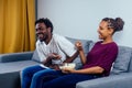 Portrait of african american young couple sitting sofa watching a movie and eating pop corn on living room Royalty Free Stock Photo