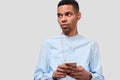 African American young man holds modern smart phone, blogging on cellphone. Handsome male listening the music on earphones Royalty Free Stock Photo