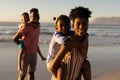 Portrait of african american young parents piggybacking daughter and son against sea and clear sky Royalty Free Stock Photo