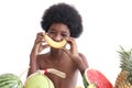 Portrait of African boy with curly hair sitting behind the row of tropical fruits. Happy smiling kid with banana in front of his Royalty Free Stock Photo