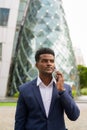 Portrait of African businessman outdoors in city talking on mobile phone Royalty Free Stock Photo