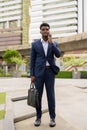 Portrait of African businessman outdoors in city talking on mobile phone Royalty Free Stock Photo