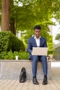 Portrait of African businessman using laptop computer outdoors in city Royalty Free Stock Photo