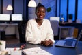 Portrait of african businessowman smiling at camera while working overtime in startup office Royalty Free Stock Photo