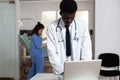 Portrait of african ethnicity doctor standing at desk with laptop