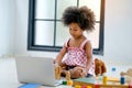 Portrait of African little girl sit in living room and play some toys in front of laptop with day light