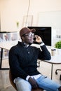 Portrait of african male executive making phone call while sitting in office. Young businessman talking on mobile phone Royalty Free Stock Photo