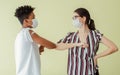 Portrait African man and Caucasian young woman making elbow bump or hit, wearing face masks, getting vaccination to protect virus Royalty Free Stock Photo