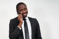 Portrait of african man smiling while talking on the phone with grey wall on background with copy space Royalty Free Stock Photo