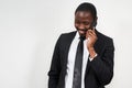 Portrait of african man smiling while talking on the phone with grey wall on background with copy space Royalty Free Stock Photo