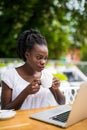 Portrait of african woman using laptop at an outdoor cafe and cup of coffee on table Royalty Free Stock Photo