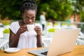 Portrait of african woman using laptop at an outdoor cafe and cup of coffee on table Royalty Free Stock Photo