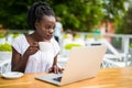 Portrait of african woman using laptop at an outdoor cafe and cup of coffee on table Royalty Free Stock Photo