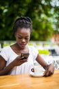 Portrait of african woman using mobile phone at an outdoor cafe with laptop and cup of coffee on table Royalty Free Stock Photo