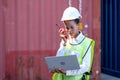 Portrait of African worker woman hold walky-talkie and laptop for her working in cargo container shipping area