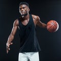 Portrait of afro american male basketball player playing with a ball over black background. Fit young man in sportswear Royalty Free Stock Photo