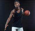 Portrait of afro american male basketball player playing with a ball over black background. Fit young man in sportswear Royalty Free Stock Photo