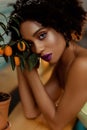Portrait of Afro-American pretty young woman with an orange tree, beutiful curly black woman with bright makeup, girl Royalty Free Stock Photo