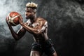 Portrait of afro-american sportsman, basketball player with a ball over black background. Fit young man in sportswear Royalty Free Stock Photo