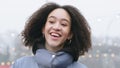 Portrait of afro american woman with curly hair stands outdoors in winter in warm outerwear exhales steam from her mouth