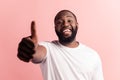 Portrait of afroamerican handsome bearded man showing thumb up sign on pink background