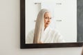 Portrait of an aged woman with long grey hair. Female looking in the mirror admires her hair Royalty Free Stock Photo