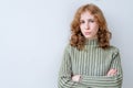 Portrait of aggravated sad woman with long red hair with crossed hands expressing her dissatisfaction and disconent. Royalty Free Stock Photo