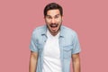 Portrait of aggressive shocked handsome bearded young man in blue casual style shirt standing looking and screaming at camera with Royalty Free Stock Photo