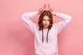 Portrait of aggressive teen girl in hoodie standing with bull horns, antler head gesture