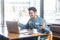 Portrait of aggressive unhappy young businessman in blue jeans shirt are sitting in cafe and having bad mood Royalty Free Stock Photo