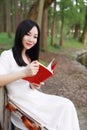 Portrait Aisan Chinese girl woman artist read book on a bench knowledge hobby violin free causal way of life park garden forest