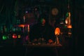 portrait of alchemist magician in interior of dark laboratory workshop with flasks and equipment