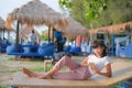 Portrait Alone Woman Take a Rest and use Mobile Smarthpone on Beach Sun bed with blur outdoor Restaurant