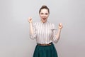 Portrait of amazed beautiful young woman in striped shirt and green skirt with makeup and collected ban hairstyle, standing and Royalty Free Stock Photo