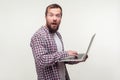 Portrait of amazed computer user, bearded man standing with laptop and looking at camera with shocked expression. studio shot Royalty Free Stock Photo