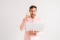 Portrait of amazed excited young man standing working on laptop computer pointing index finger up with happy face on Royalty Free Stock Photo