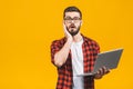 Portrait of amazed man holding laptop computer and looking at camera over yellow background Royalty Free Stock Photo
