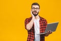 Portrait of amazed man holding laptop computer and looking at camera over yellow background Royalty Free Stock Photo