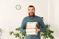 Portrait of amazed office worker man holding a bunch of books