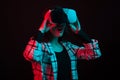 Portrait of amazed teenage girl with vr headset in studio and color light over black background