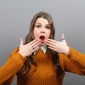 Portrait of a amazed woman with spread hands against gray background Royalty Free Stock Photo