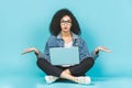 Portrait of amazed young afro american woman using laptop while sitting on a floor with legs crossed isolated over blue background Royalty Free Stock Photo