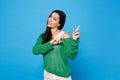 Portrait of amazed young woman in green casual clothes looking camera and pointing index fingers aside isolated on Royalty Free Stock Photo