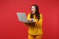 Portrait of amazed young woman in yellow fur sweater keeping mouth wide open using laptop pc computer isolated on bright Royalty Free Stock Photo