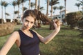 Portrait amazing attractive young woman in sportswear playing with her long curly hair in park of tropical city. Looking